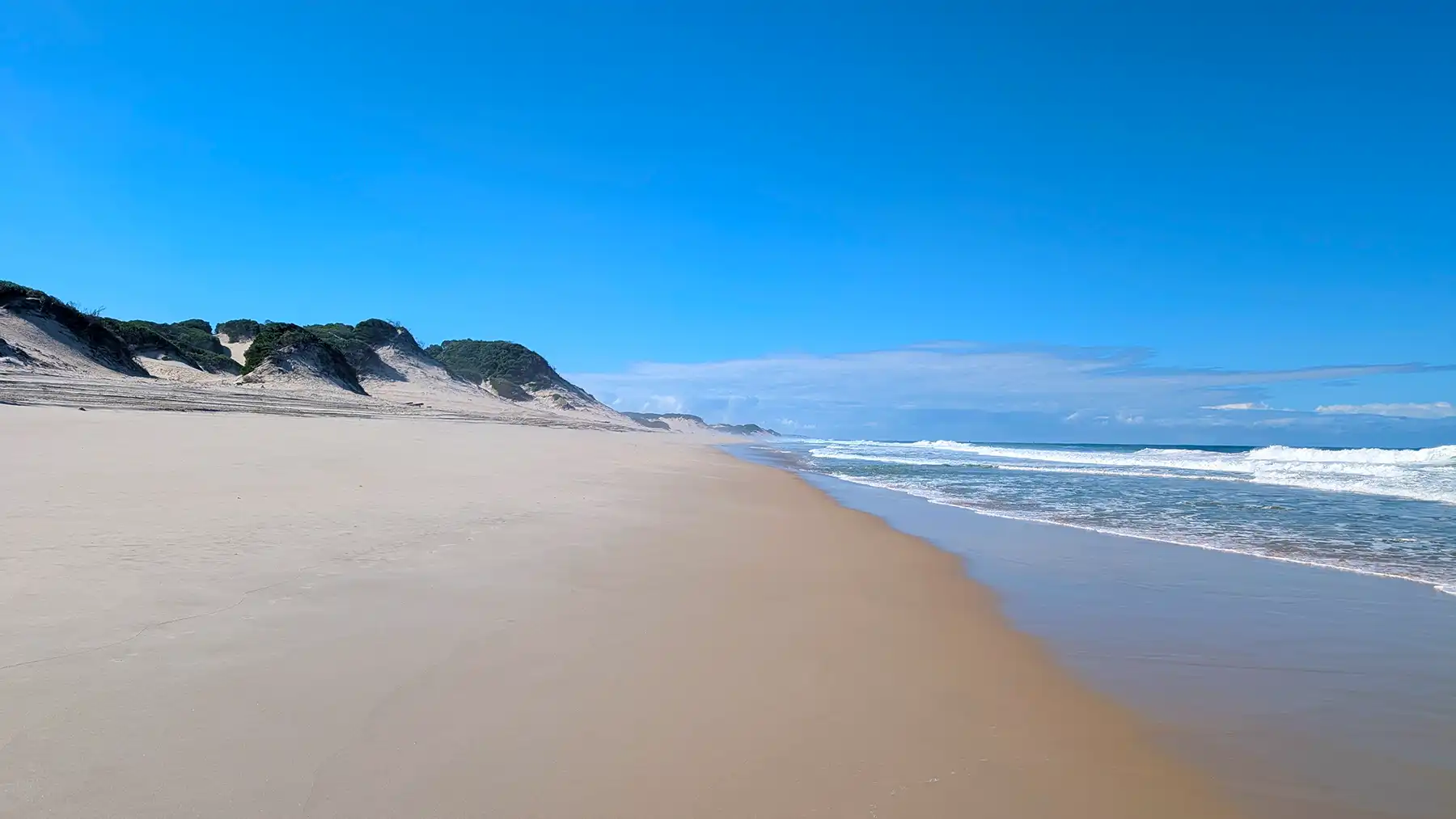 Where soft sands meet rolling dunes, Calanga’s wild coastline stretches endlessly under the warm, fading light.
