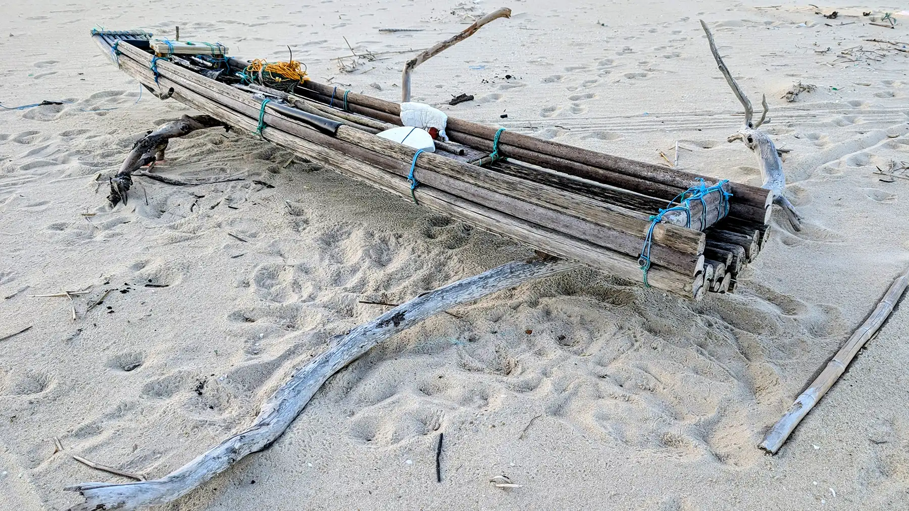 A handcrafted fishing boat of woven branches rests on the quiet beach, poised between tradition and tide, waiting for its fisherman to return to the sea.